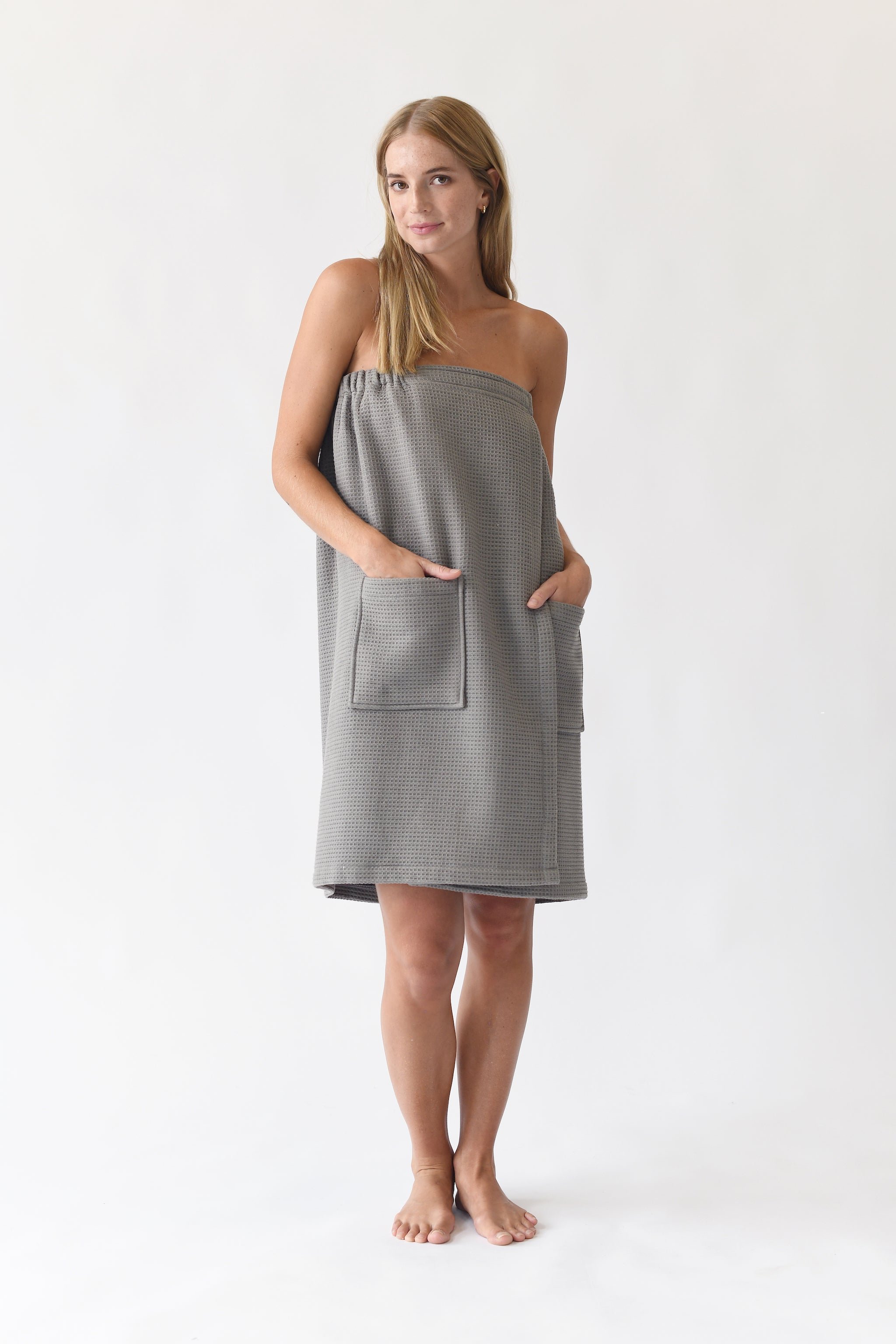 Charcoal Waffle Bath Wrap. The bath wrap is shown being worn by a woman. Photo was taken with a white background.