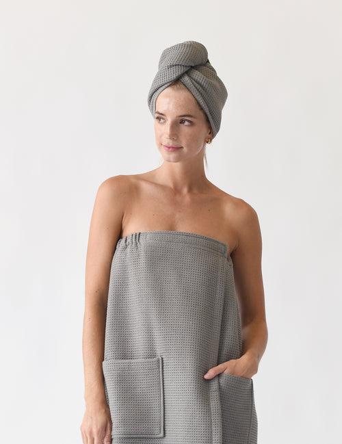 Charcoal Waffle Hair Towel. The hair towel is shown being worn by a woman who is also wearing a waffle bath wrap. Photo was taken with a white background.|Color:Charcoal