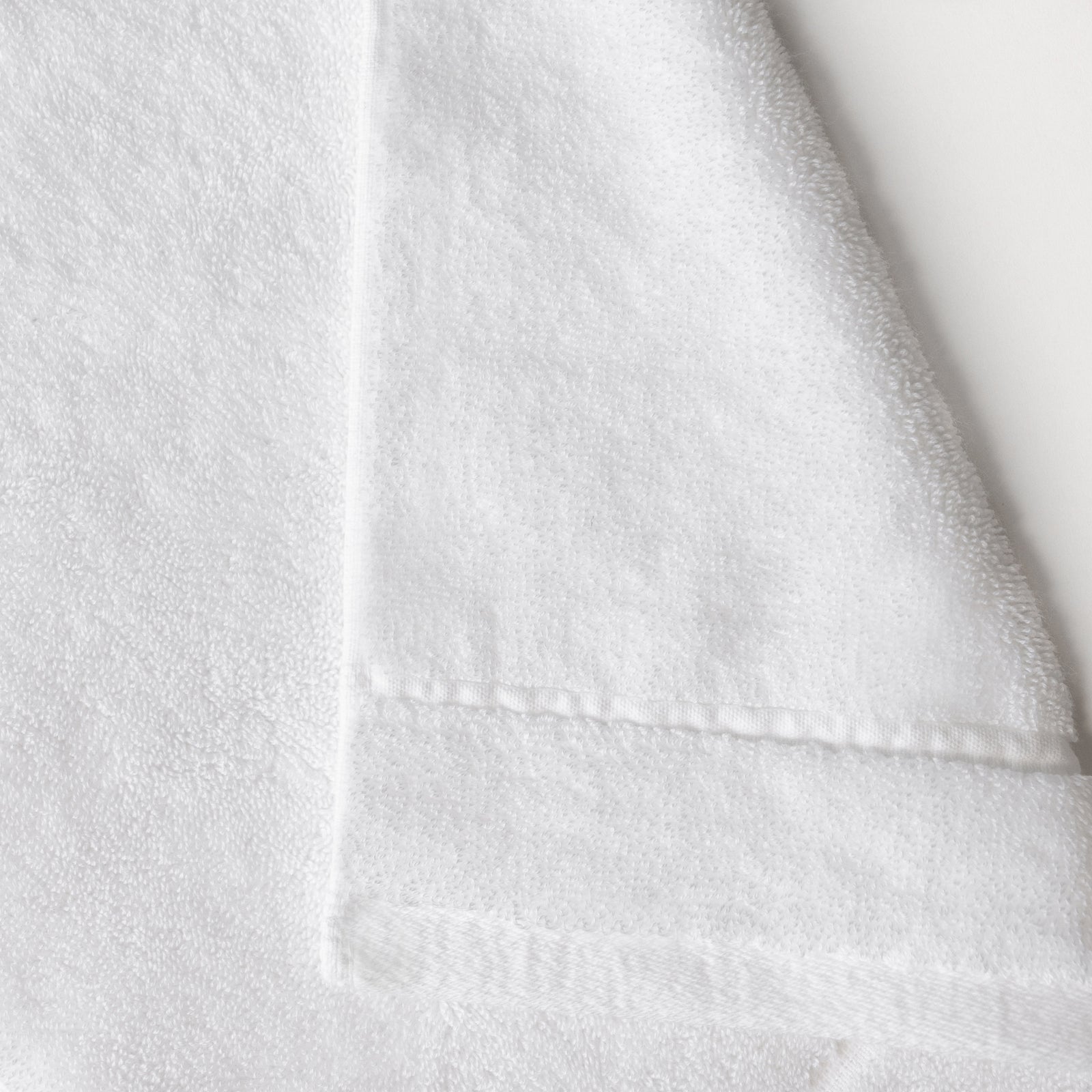 White Premium Plush Bath Towel. Photo of Premium Plush Bath Towels taken on a white background showing only the corner of the towel. 