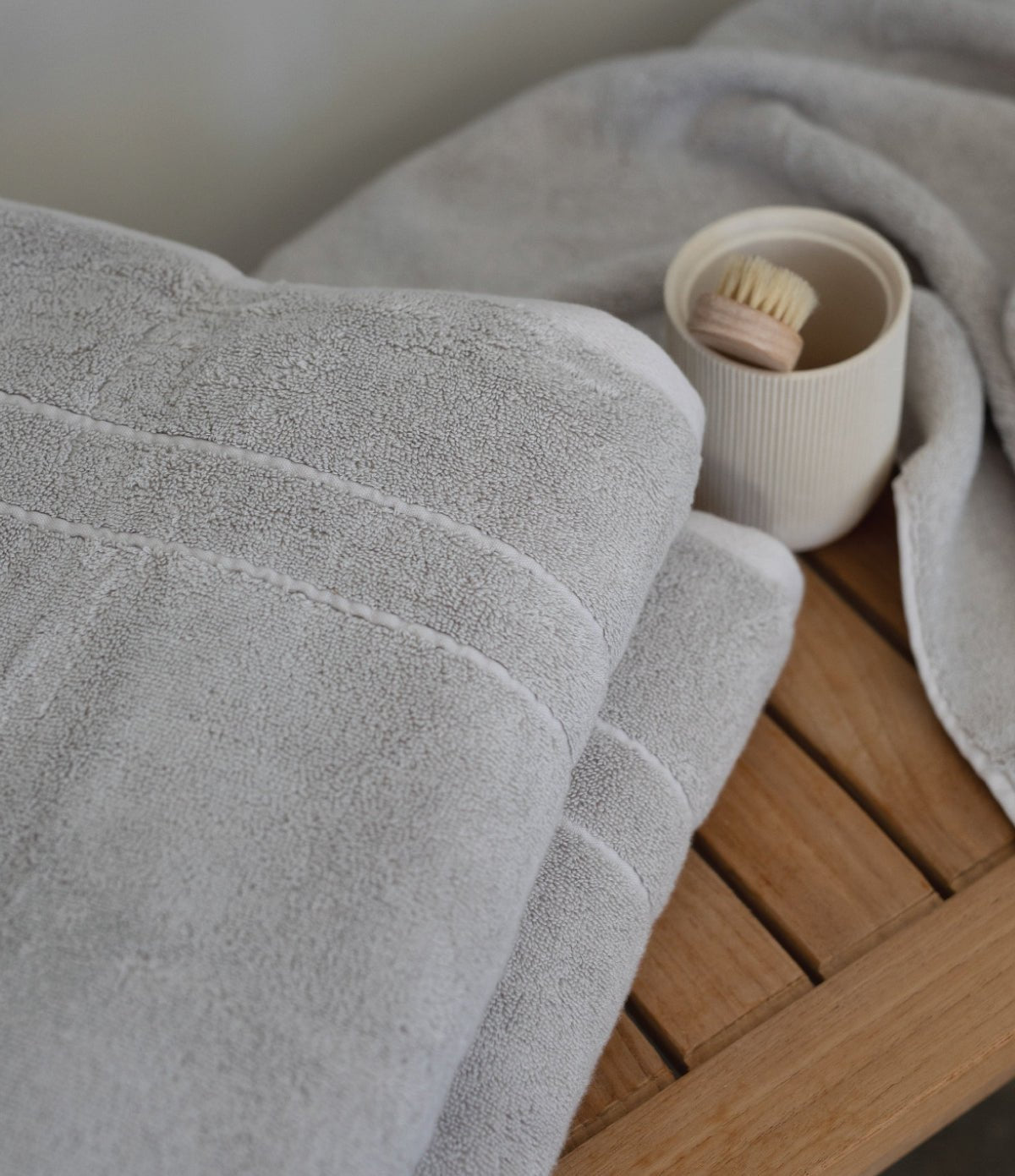 Light Grey The Premium Plush Bath Sheet folded on a wooden bench. Bath products are resting on the bench as well. 