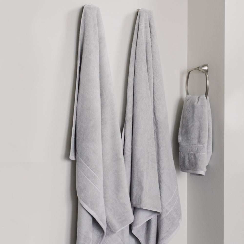 Premium Plush Bath Sheets in the color Light Grey. Photo of Premium Plush Bath sheets taken in a bathroom showing the towels which are hung from a towel rack. 
