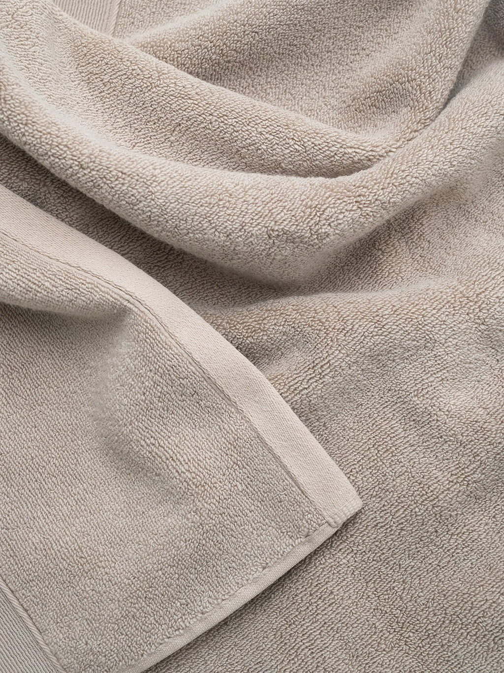 Close-up of a soft, beige, textured fabric with folds.