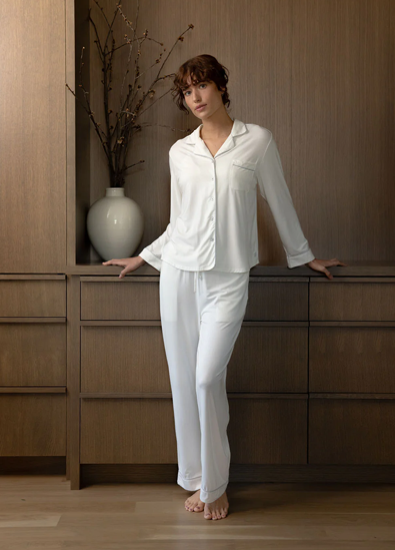 Person wearing white pajamas, leaning against wooden furniture.