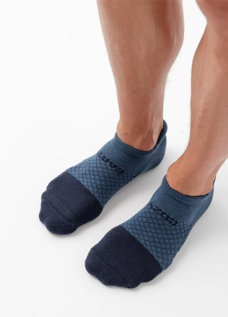 Person wearing blue athletic ankle socks on a white background.
