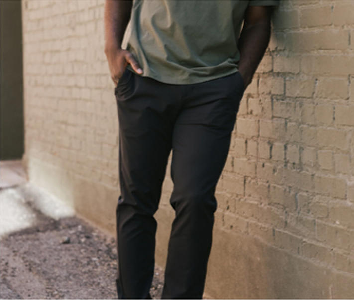 Person in casual attire leaning against a brick wall outdoors.