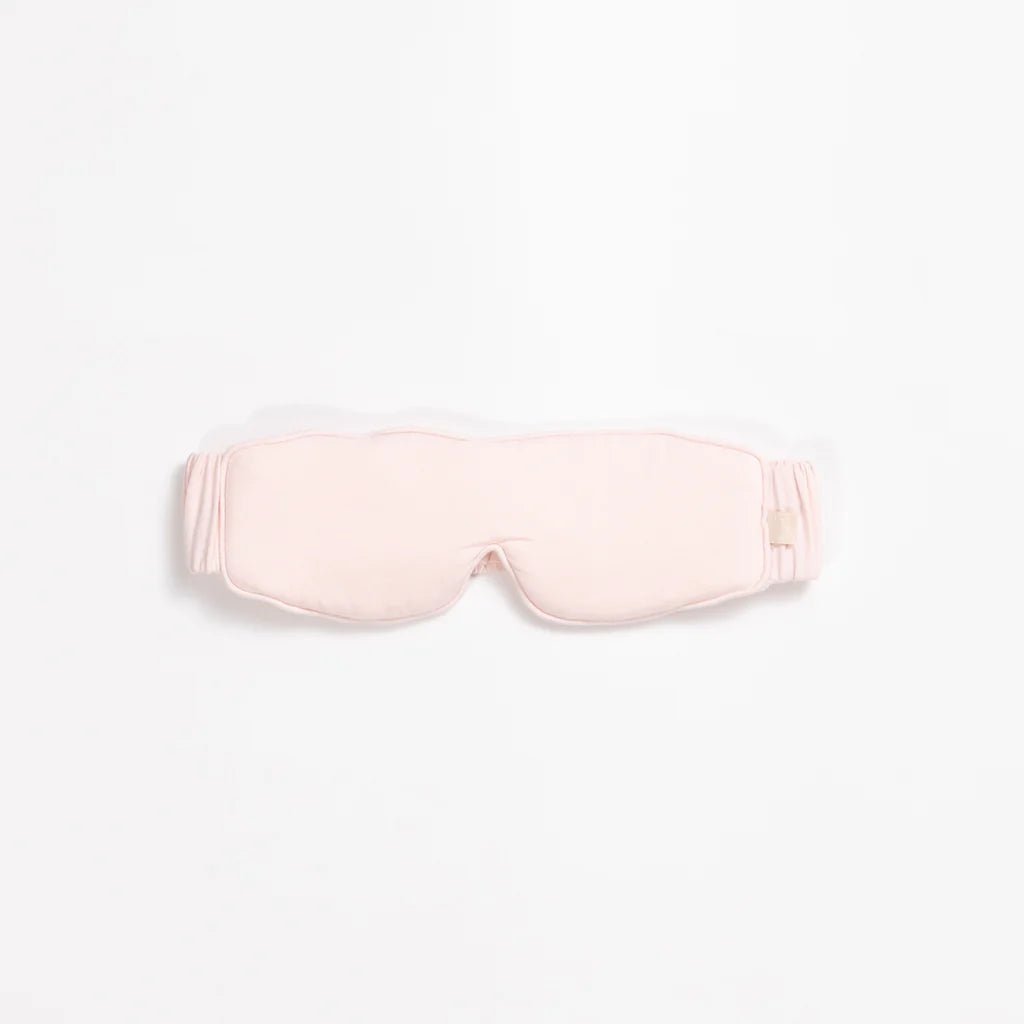 Pink silk sleep mask with an elastic strap on a white background.