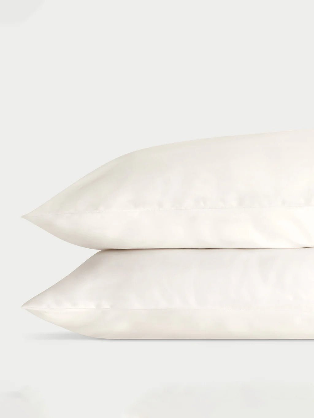 Two stacked white pillows against a plain background.