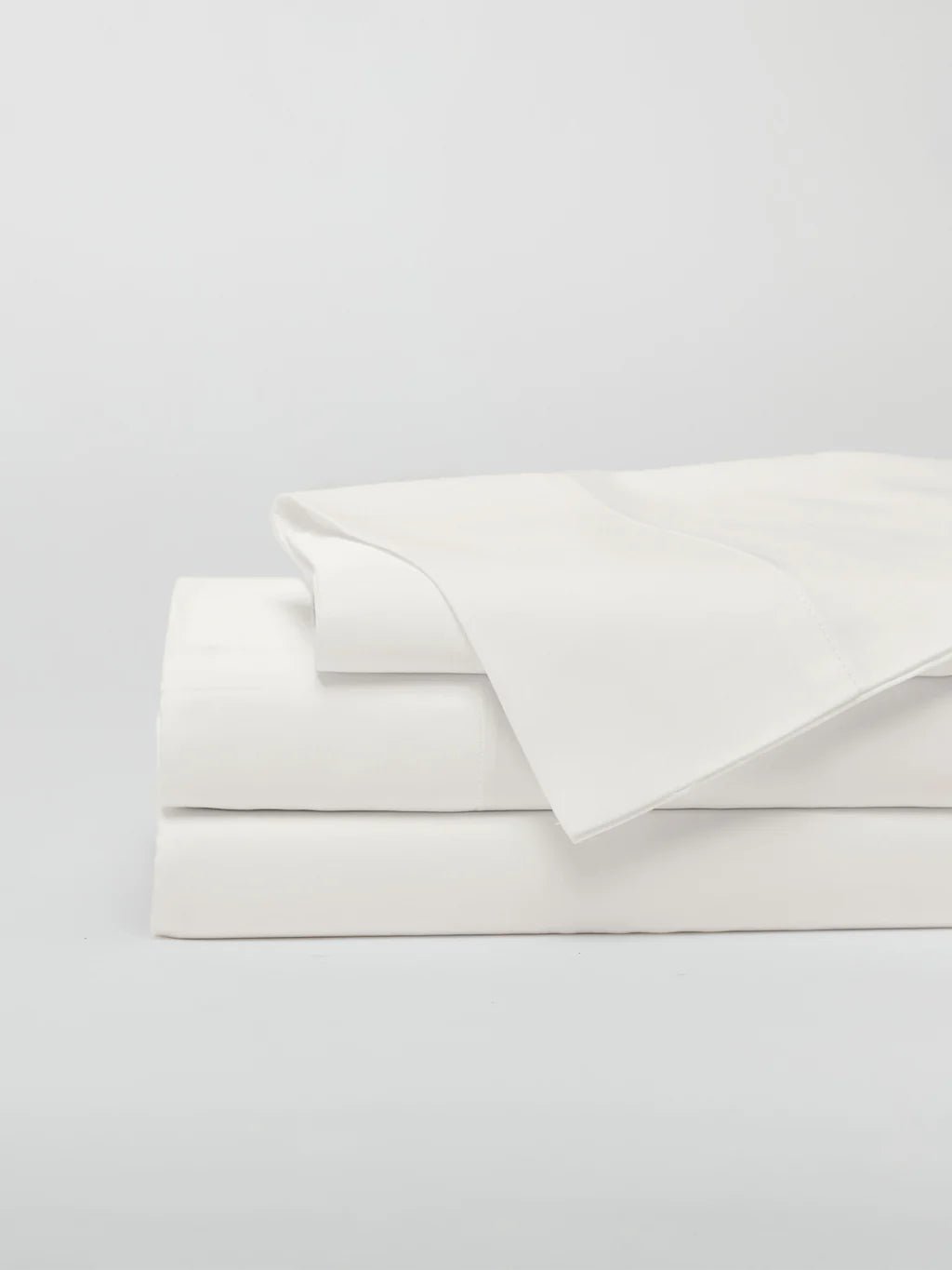 Stack of folded white bed sheets.