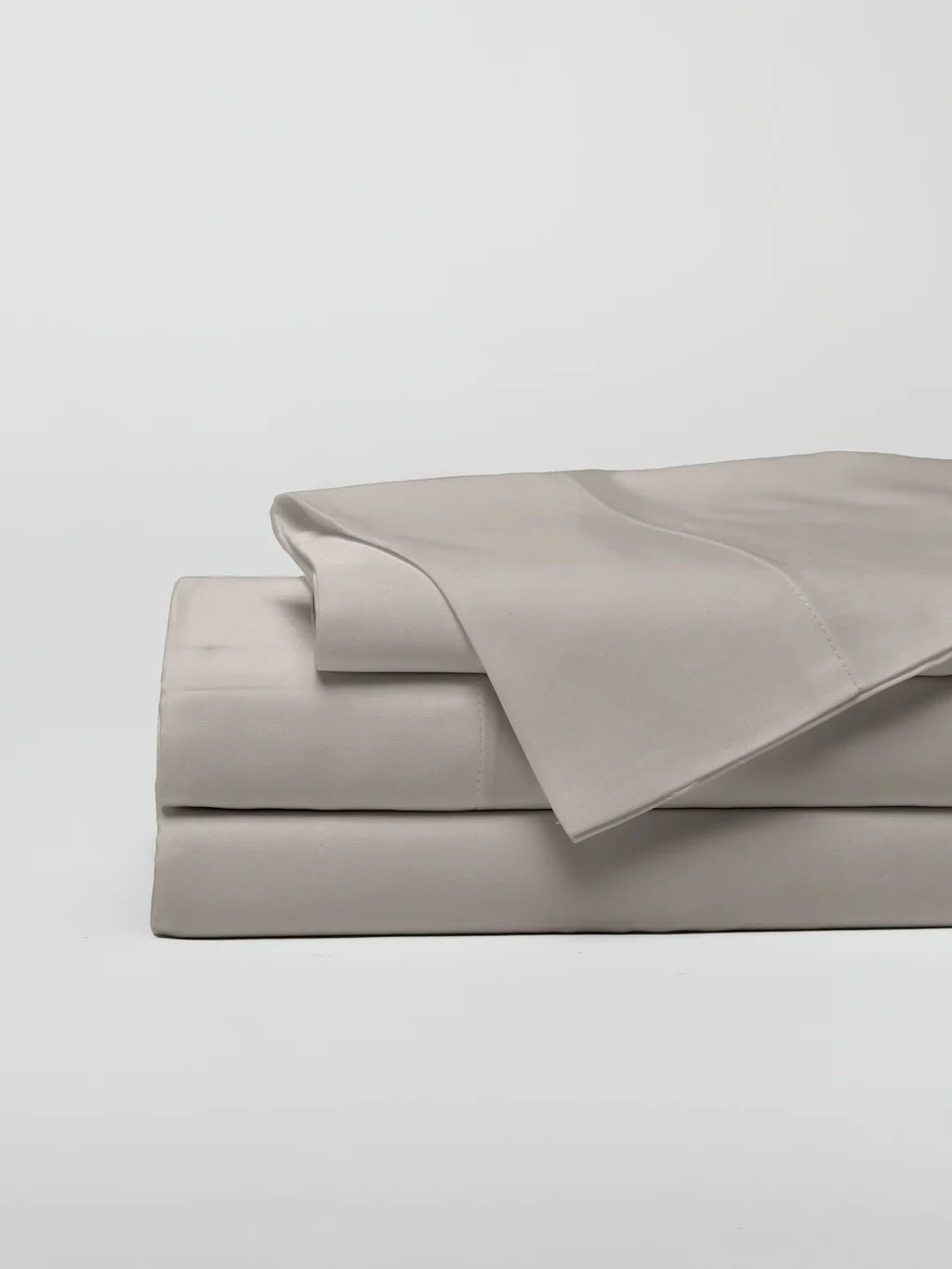 A stack of neatly folded cream-colored bed sheets.