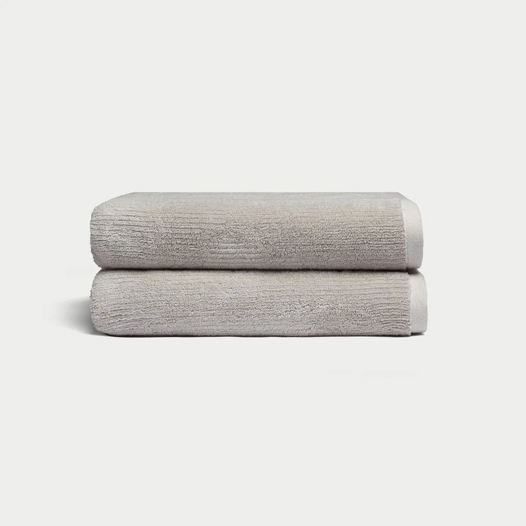 Two neatly folded beige towels stacked on a light background.