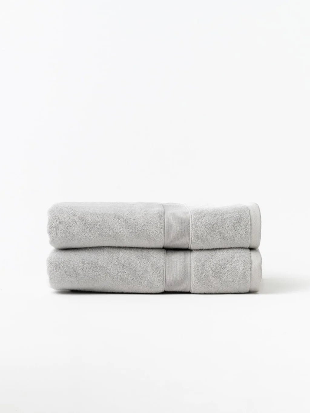 Two neatly stacked, light gray towels on a white background.