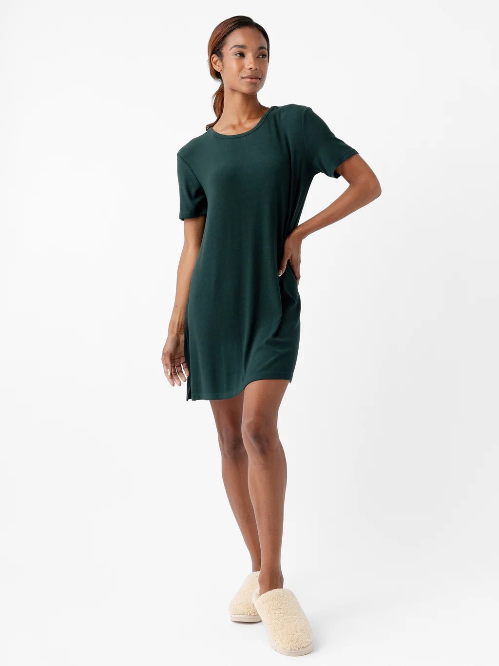 Person wearing a green dress and beige slippers on a white background.