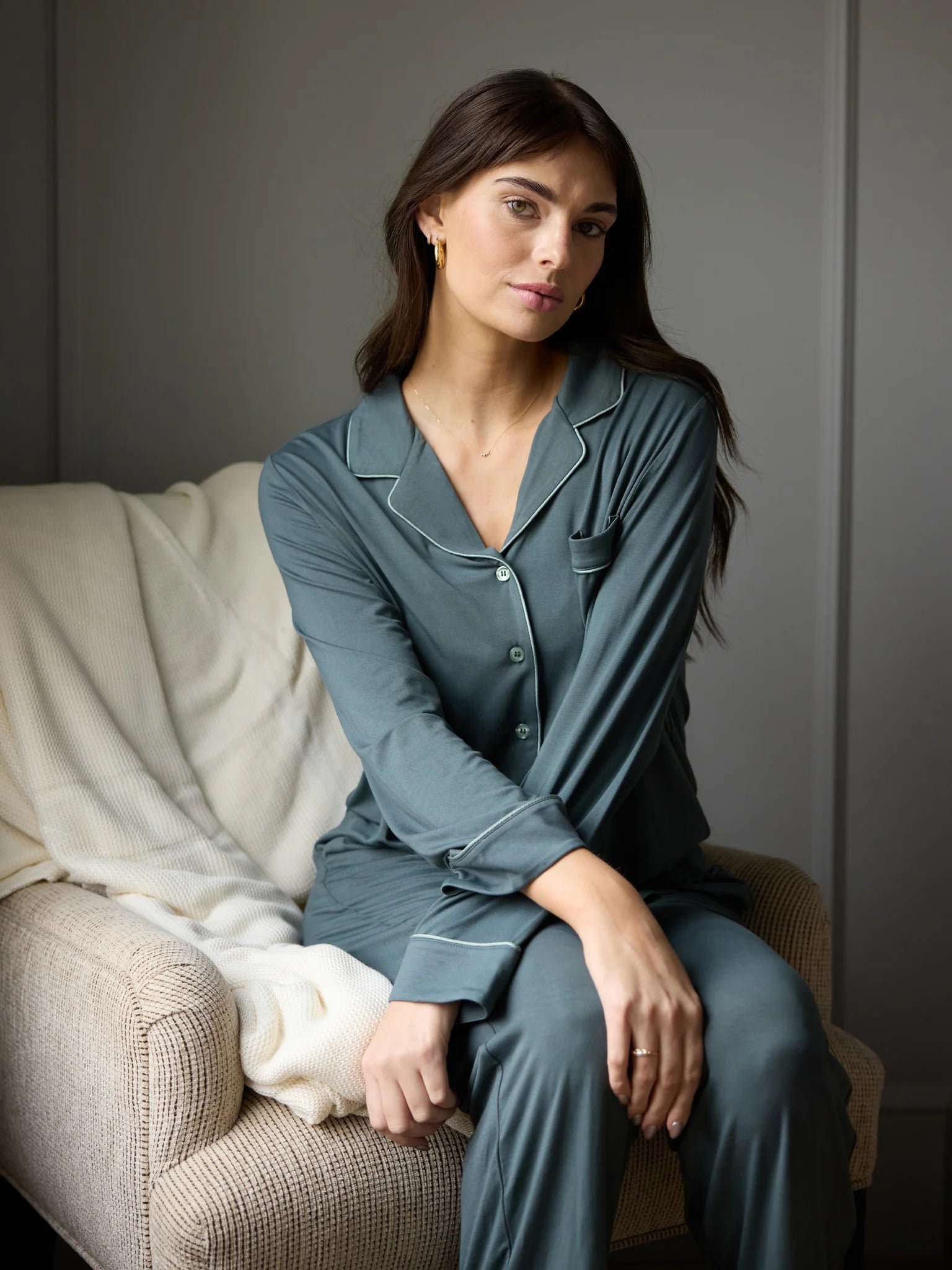 Pregnant woman standing by a crib, looking down, with sunlight shining through the window.