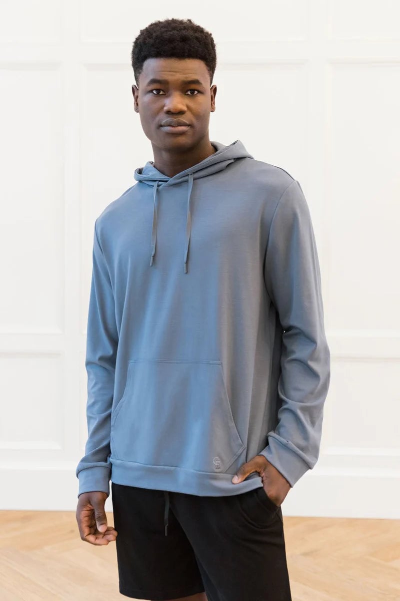 Person wearing a light blue hoodie with hands in front pocket, standing indoors.