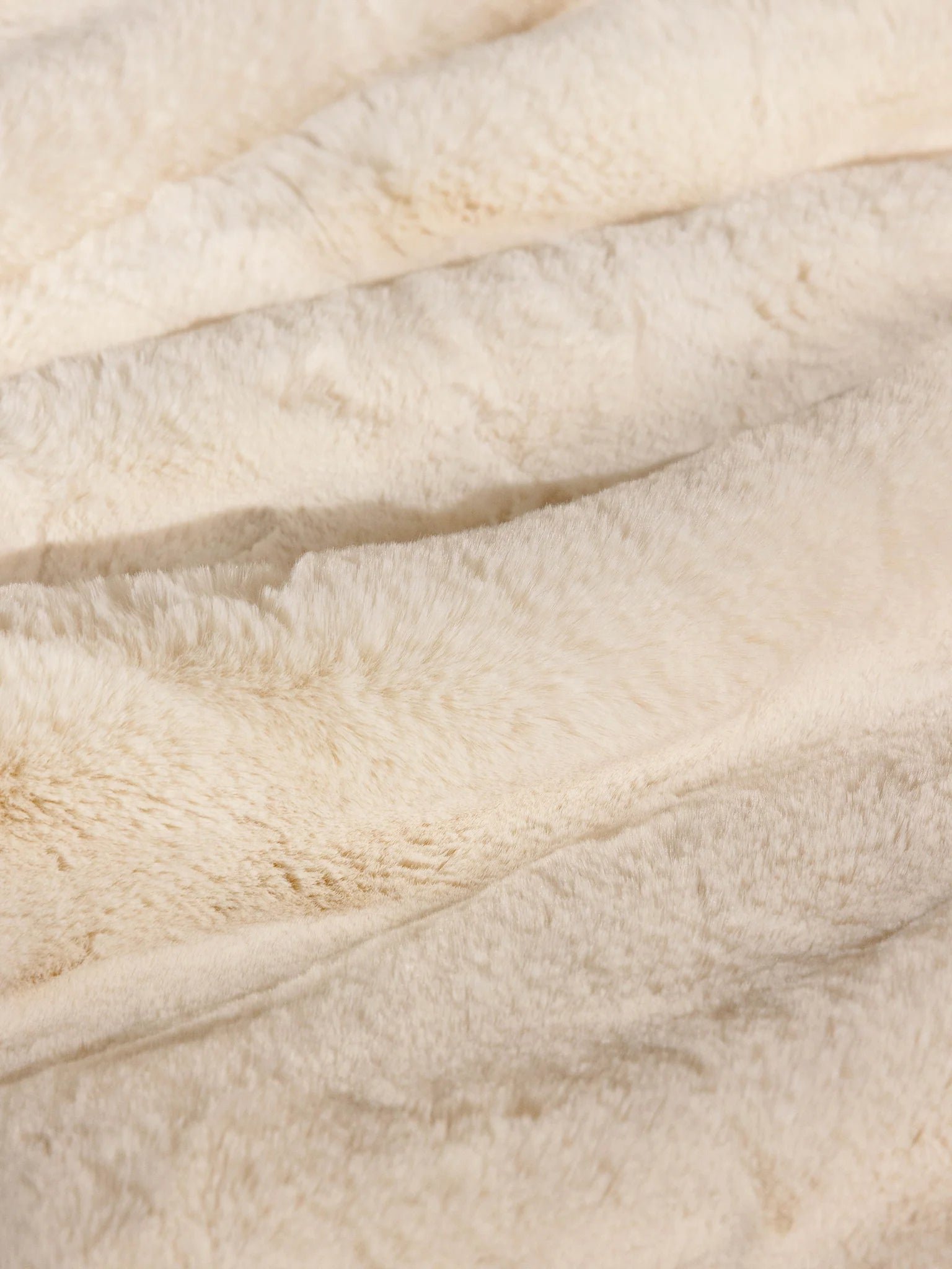 Close-up of soft, cream-colored faux fur fabric texture.