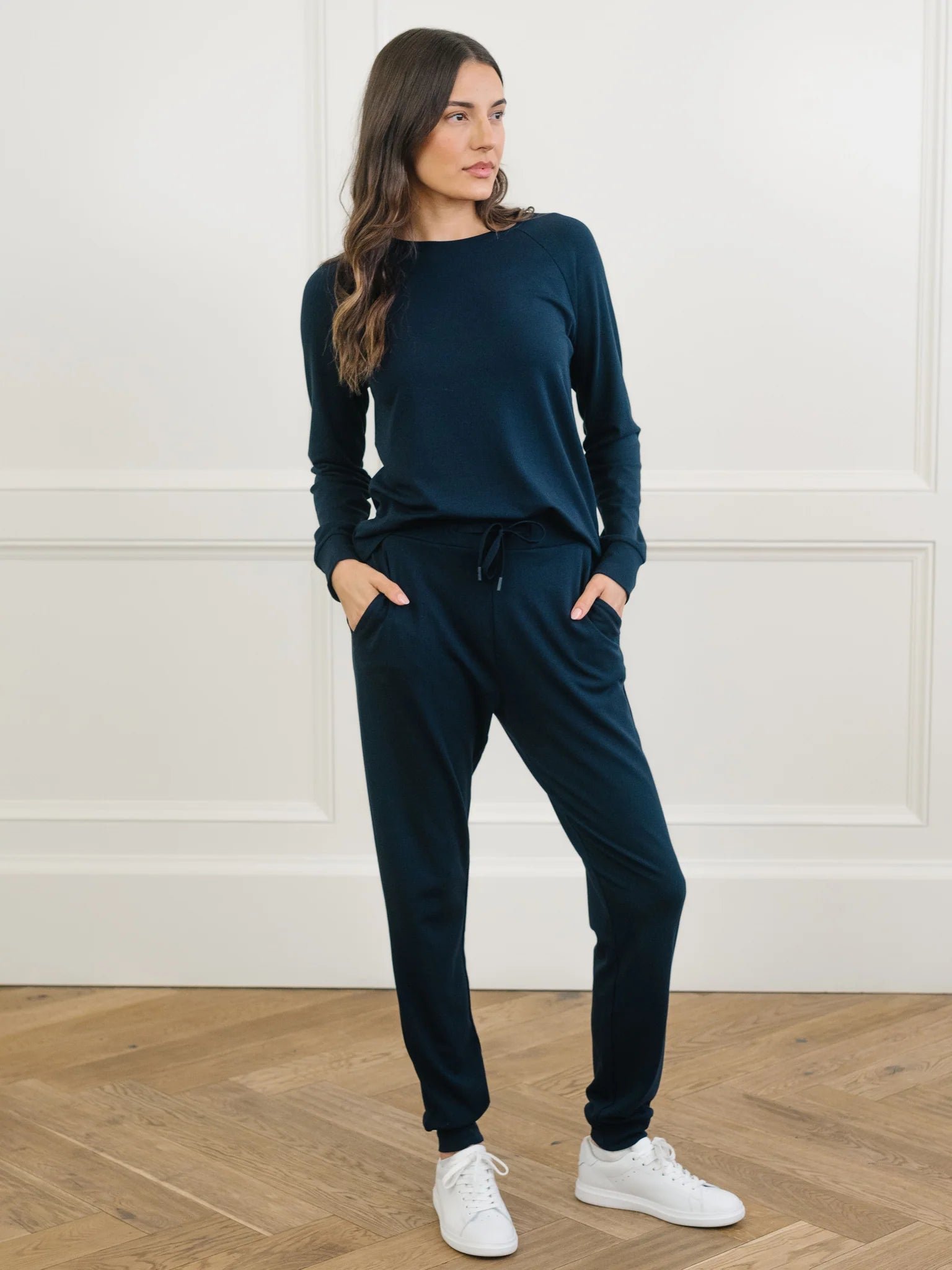 Woman wearing a navy blue lounge set with white sneakers.