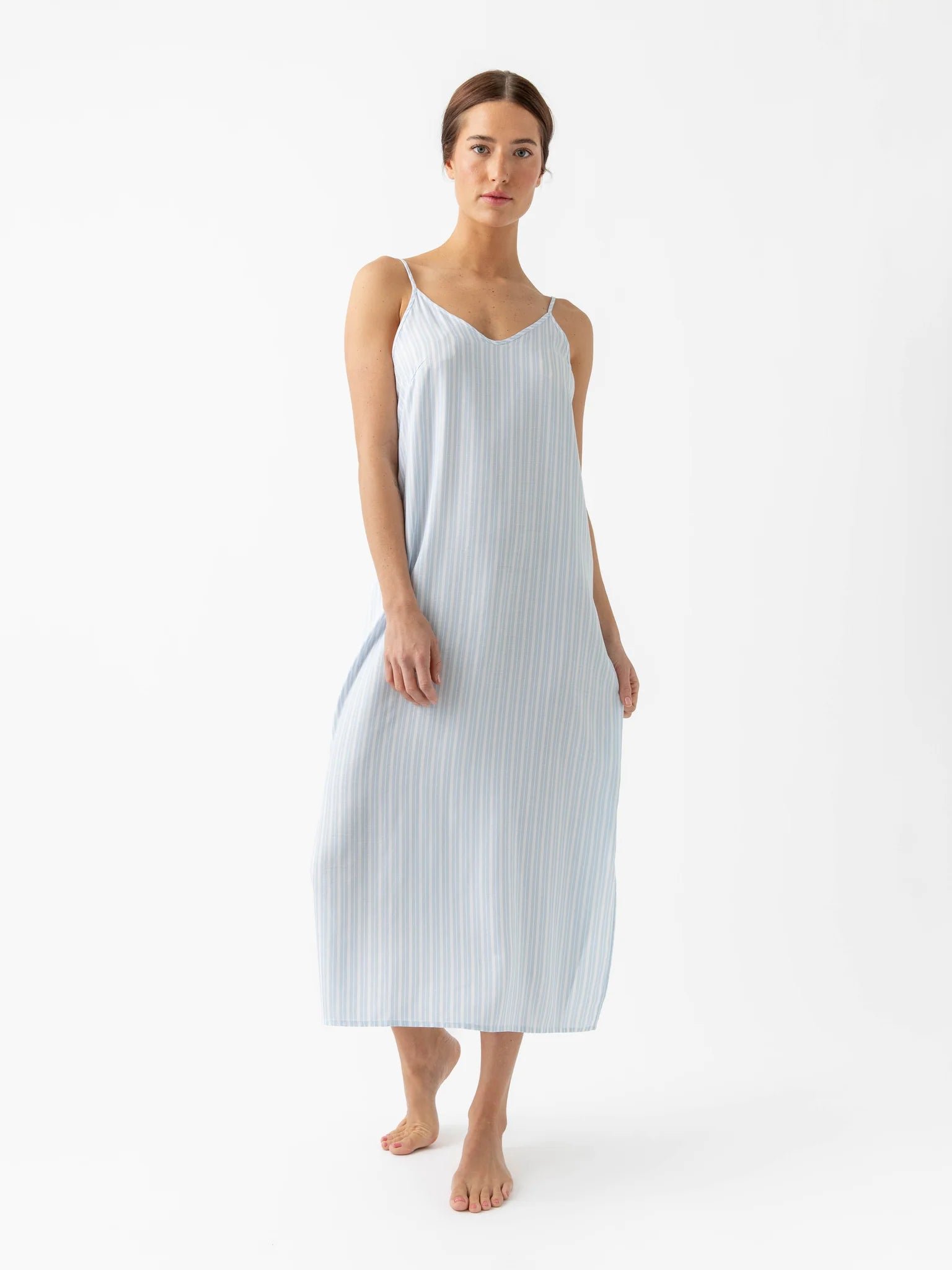 Woman wearing a light blue and white striped sleeveless dress.