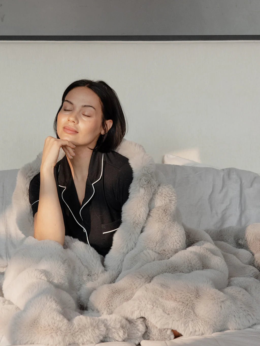 Person relaxing in bed, wrapped in a fluffy blanket.