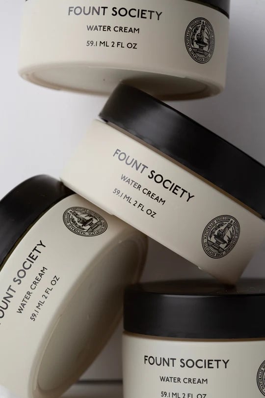 Containers of Fount Society water cream stacked together.