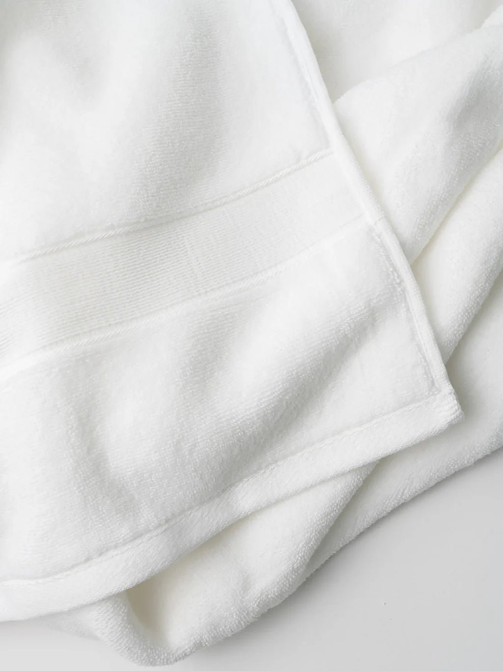 Soft, white folded towel on a smooth surface.