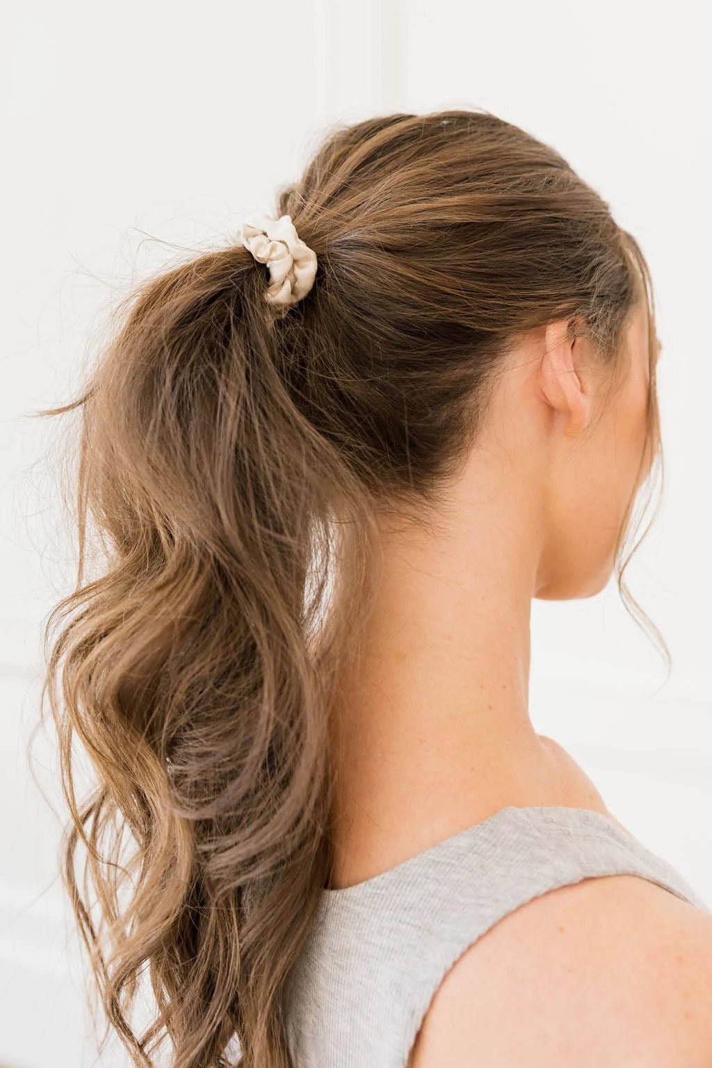 Woman with brown hair in a ponytail, held by a scrunchie.
