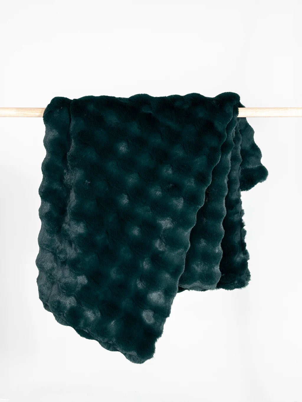 Dark green, textured fur blanket draped over a wooden rod.