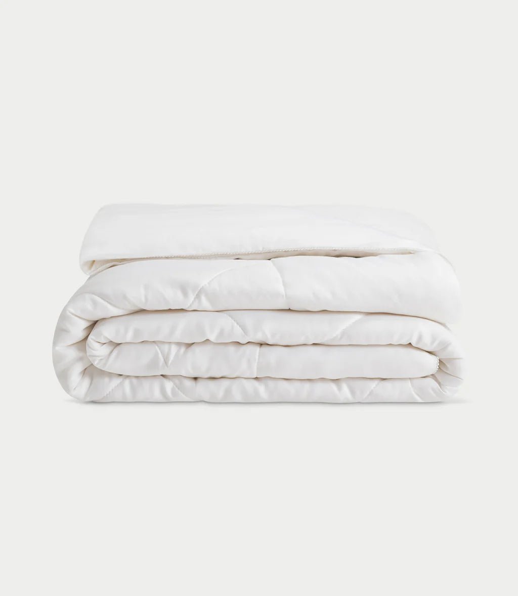 A neatly folded white comforter on a plain background.
