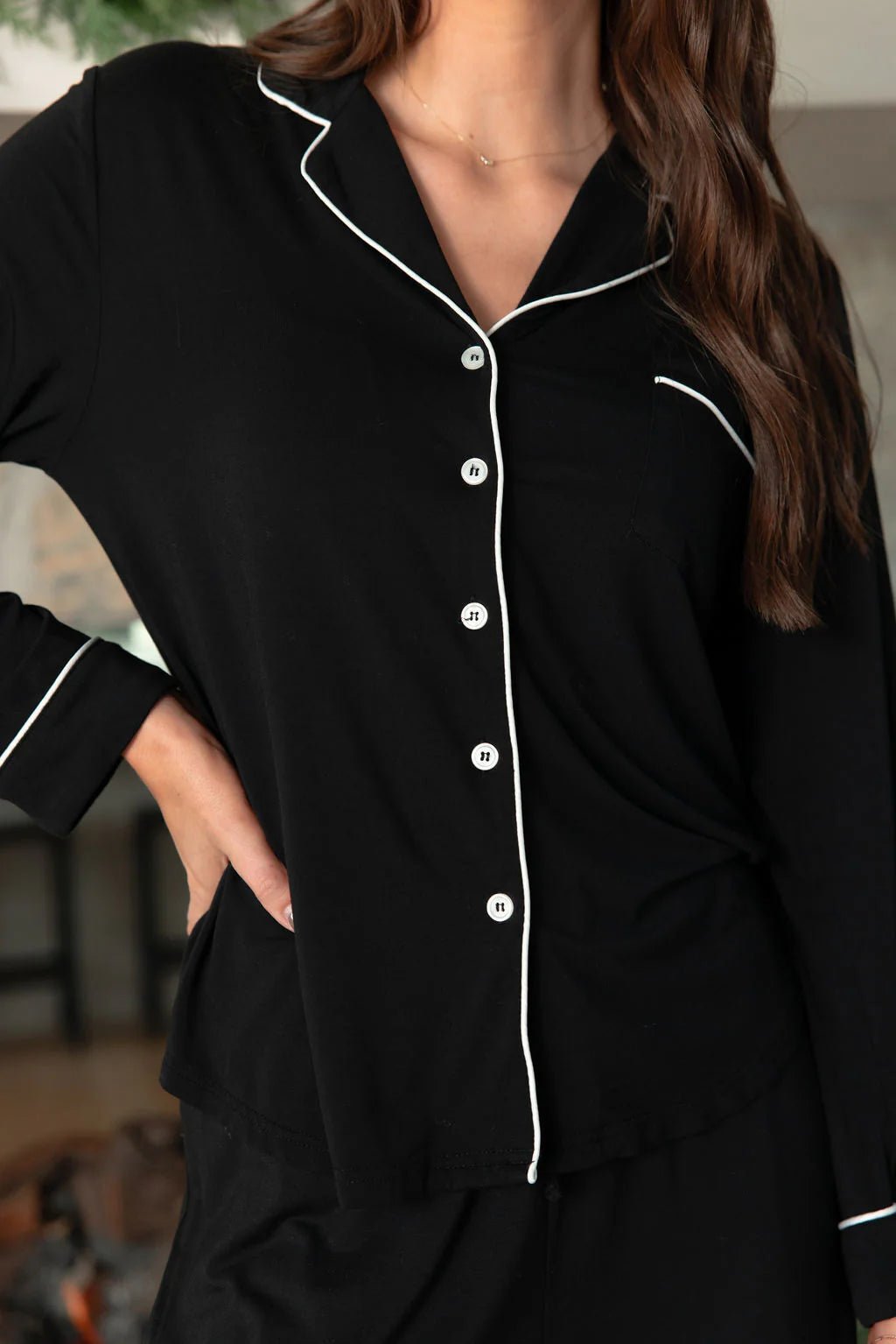Woman wearing a black pajama shirt with white piping.