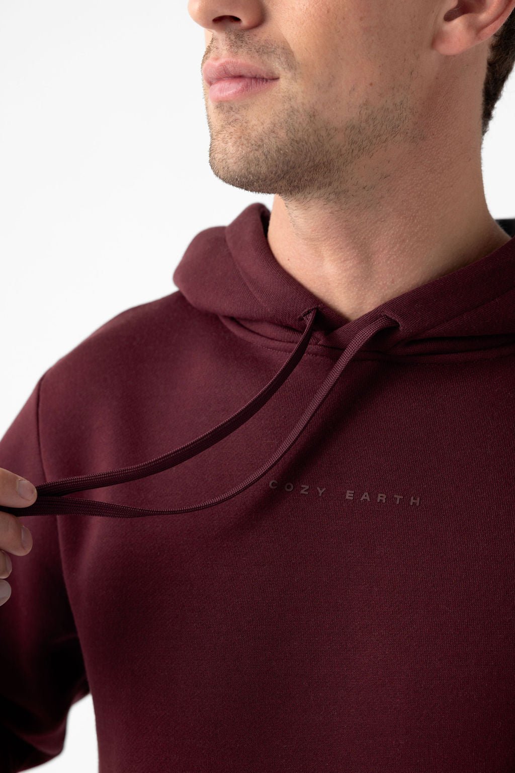 Person wearing a burgundy Cozy Earth hoodie, focusing on the chest area and logo.