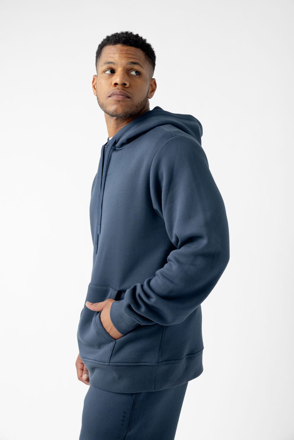 Man wearing a blue hoodie with his hands in the front pocket.