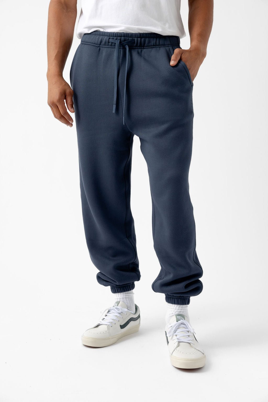 Person wearing dark blue joggers, white socks, and white sneakers.