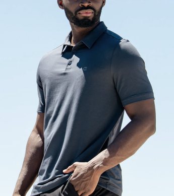 Man wearing a dark grey polo shirt against a clear blue sky background.