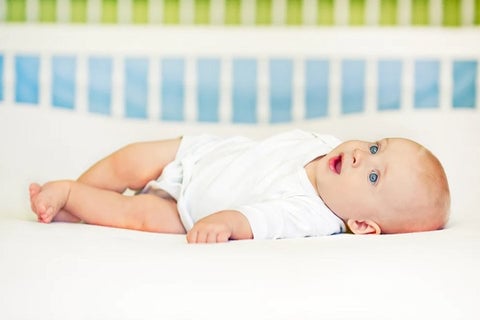 Baby laying on back in crib