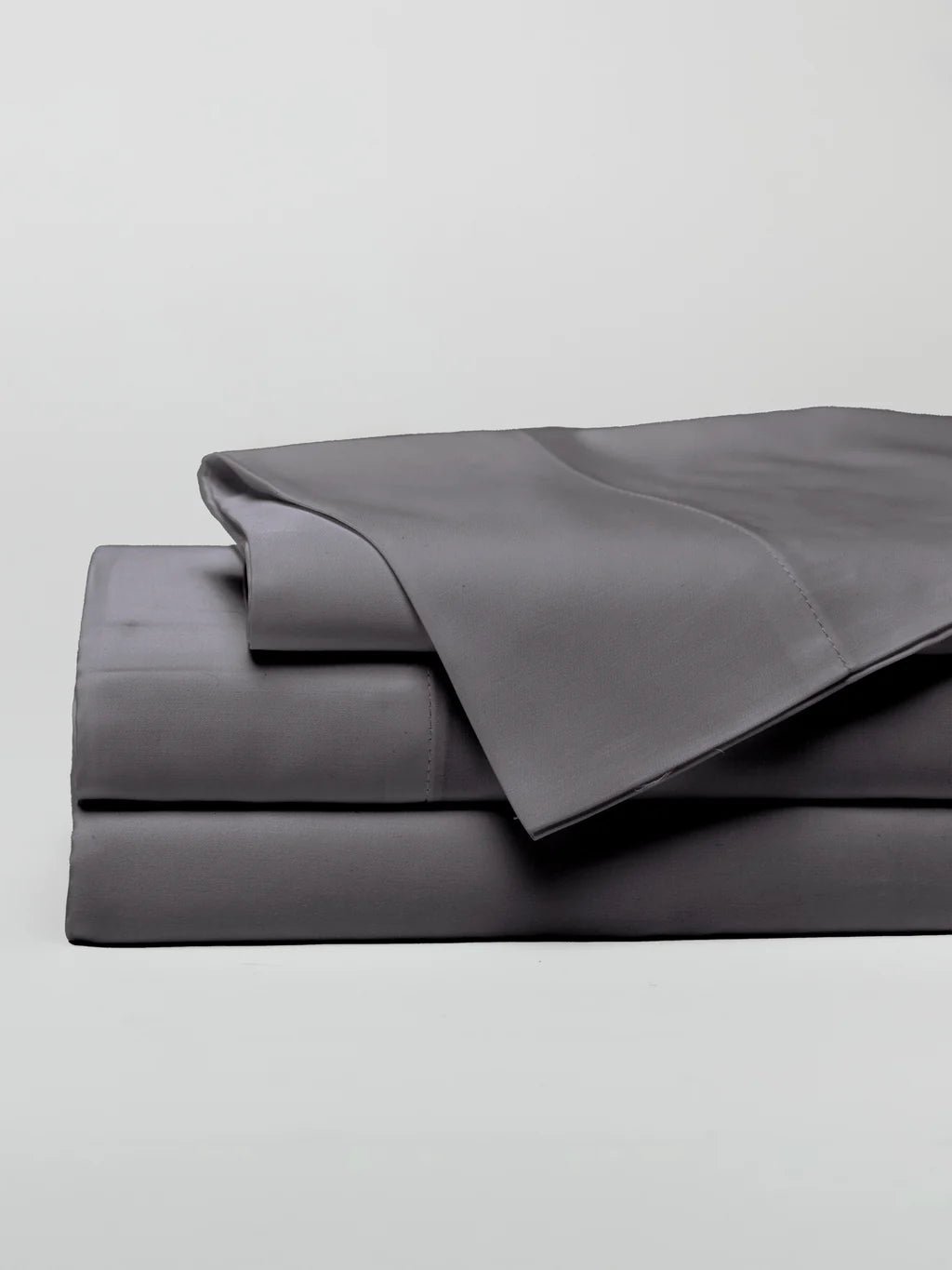 Folded gray bedsheets stacked neatly in a minimalist setting.