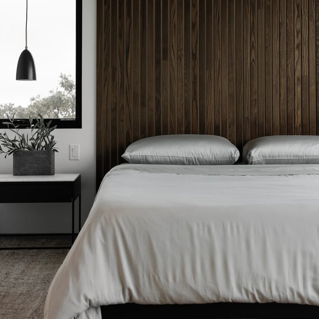 A modern bedroom with a wooden accent wall and minimalist decor.