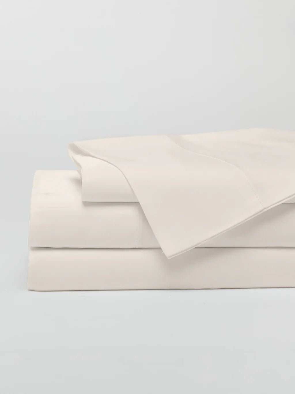 Stack of white folded bed sheets on a plain background.
